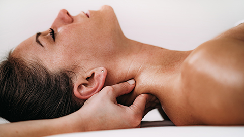 A woman receiving a neck massage while lying on her back