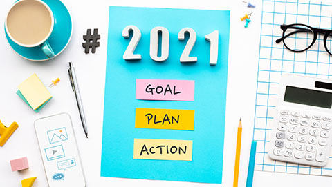 Goal, Plan, Action on a board surrounded by an array of office supplies