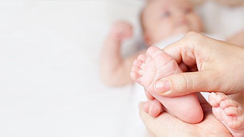 An image of a baby with their foot in the foreground receiving pediatric touch.