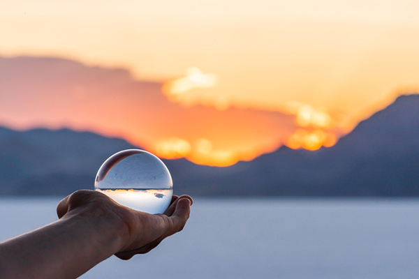 colorful landscape background with hand holding crystal ball near Salt Lake City, Utah and mountain view and sunset 
