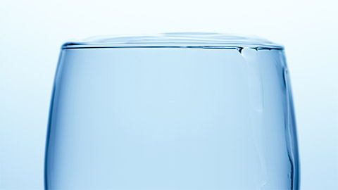 A glass of water that is just about to overflow.