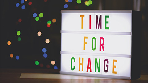 A holiday sign with the words time for change in colorful lettering.