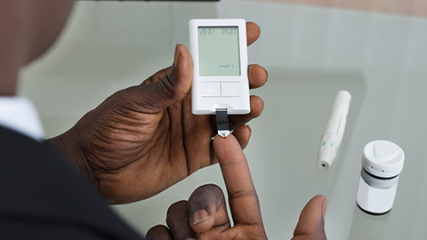 African American man checking blood sugar with a glucose monitor.