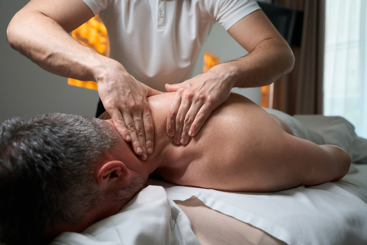 A massage therapist works on a client's neck area.