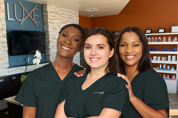 Three massage therapists pose for a photo at a Massage Luxe studio.
