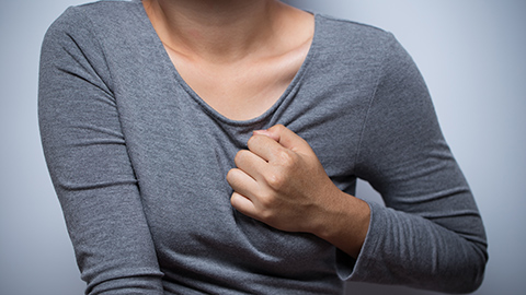 A woman clutching the left side of her chest in pain