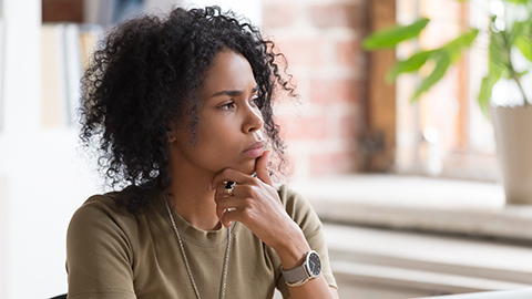 A woman with her chin in her hand thinking 