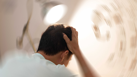 Man holding his head as everything swirls around him 