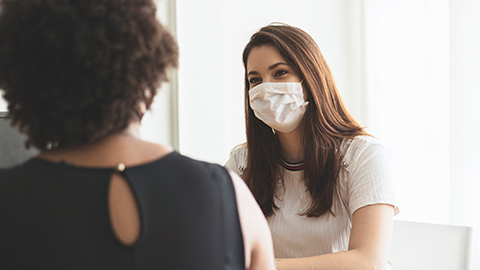 Two women wearing face masks having a conversation