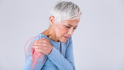 Mature woman holding a painful shoulder that is glowing red 