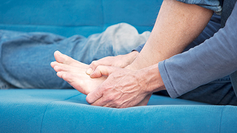 A client grasping their left foot in pain.