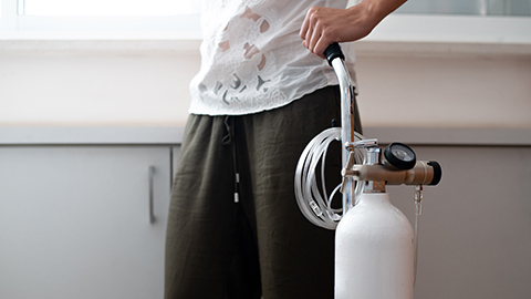 A woman holding a portable oxygen tank.