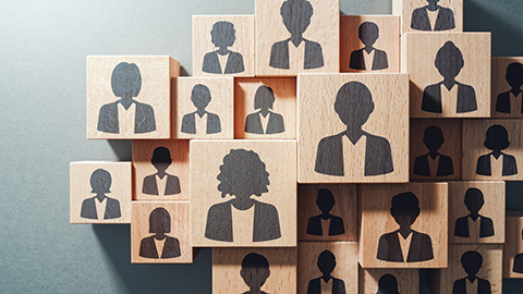 Wooden blocks etched with images of employees cast in a shadow.