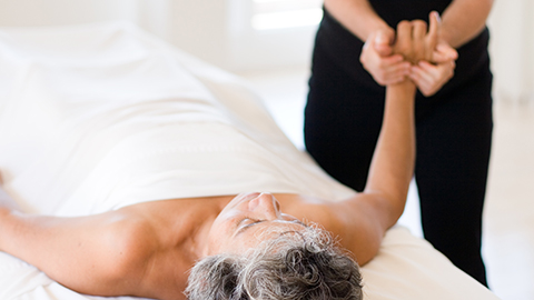 An image of an elderly woman laying supine getting bodywork performed by a massage therapist.