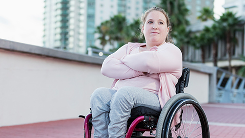 A woman with spina bifida sitting outside in a wheel chair.