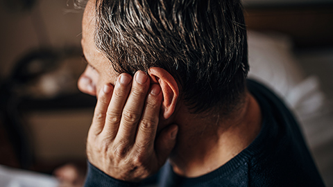 A man holding his left ear in pain.