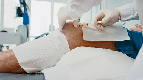 A man receiving and injection into his knee at a hospital.