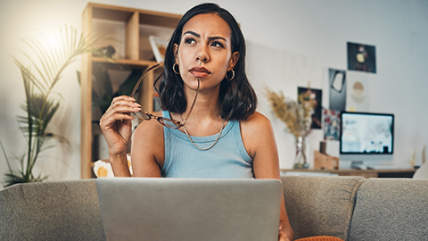 A thoughtful woman holding glasses to her mouth thinking about her business.