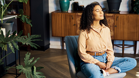 A woman sitting in a chair with her eyes closed in deep thought.