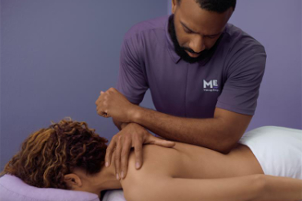 African American massage therapist using his elbow to massage a client