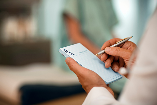 A doctor writing a note on a prescription pad.