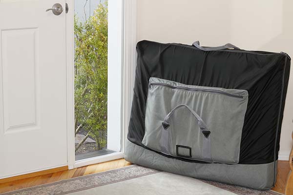 A portable massage table inside a case sitting next to an open door