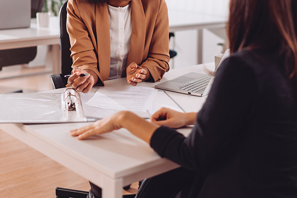 Two women talking over business reports 