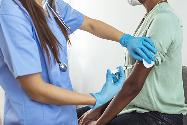 Black woman receiving a vaccine shot in her arm