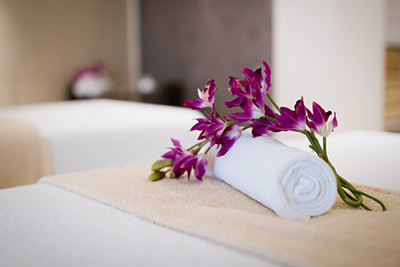 Spa treatment room with a white towel and purple flowers on a massage table