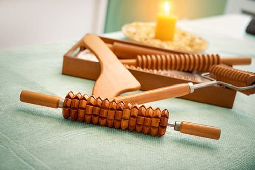 An assortment of wooden massage tools in a tranquil spa setting