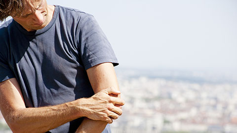 A man with elbow pain holding his elbow