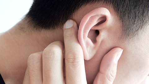 Close-up of a man rubbing the back of his ear. 