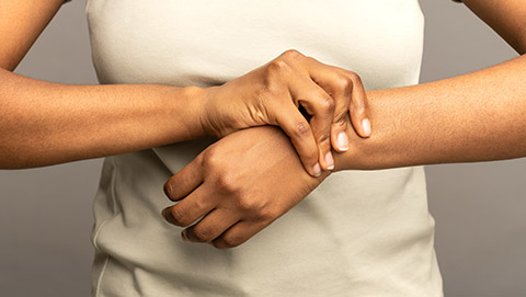 A woman holds her wrist due to joint pain.
