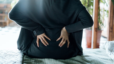 Image of a woman pressing her hands against her lower back.