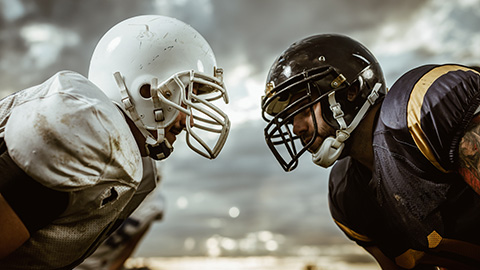 An image of two football players standing eye-to-eye.