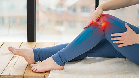 A person holding their left knee with an animated image of inflammation radiating downward.