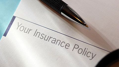 An image of a pen resting on a packet for insurance policy information.