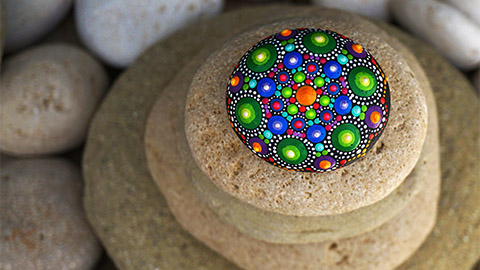 Image of rocks stacked with the top rock having a colorful design.