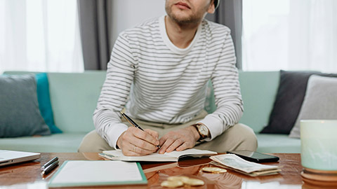 Image of a person thinking and writing in a journal.