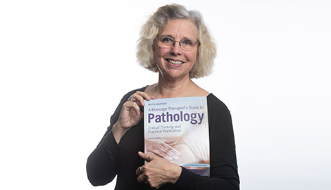 Author and educator Ruth Werner holding her book A Massage Therapist’s Guide to Pathology.