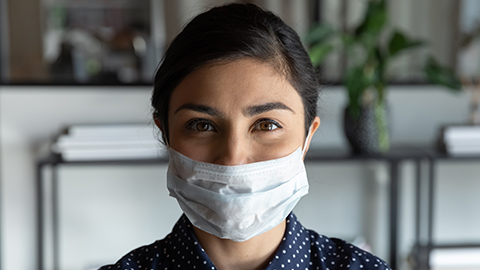 Woman wearing a paper surgical face mask in an office 