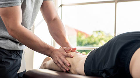 Massaging the leg of a client lying on a massage table