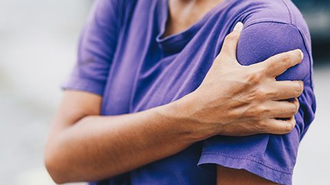 Massage client holding a painful shoulder.