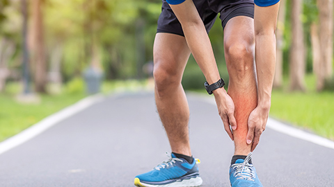 Runner holding a painful shin splint glowing red.