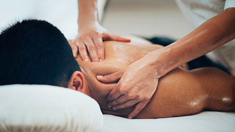 Massage therapist massaging a client's shoulder. 