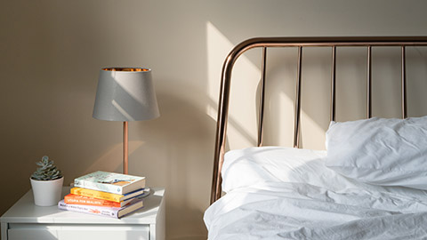 A bed and a nightstand table with books and a lamp. 