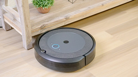 A Roomba robot vacuum on a smooth hardwood floor.