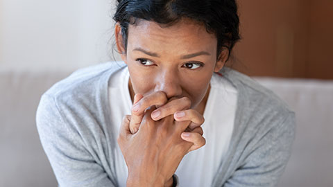 Woman with hands clenched near face, looking anxious
