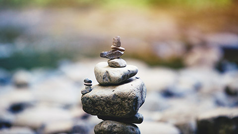 Small stones balanced in stacks near a river.