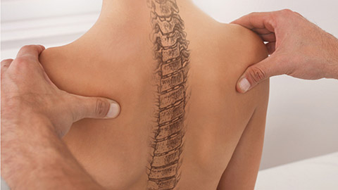 A doctor examining a woman's back with the spine drawn on the back